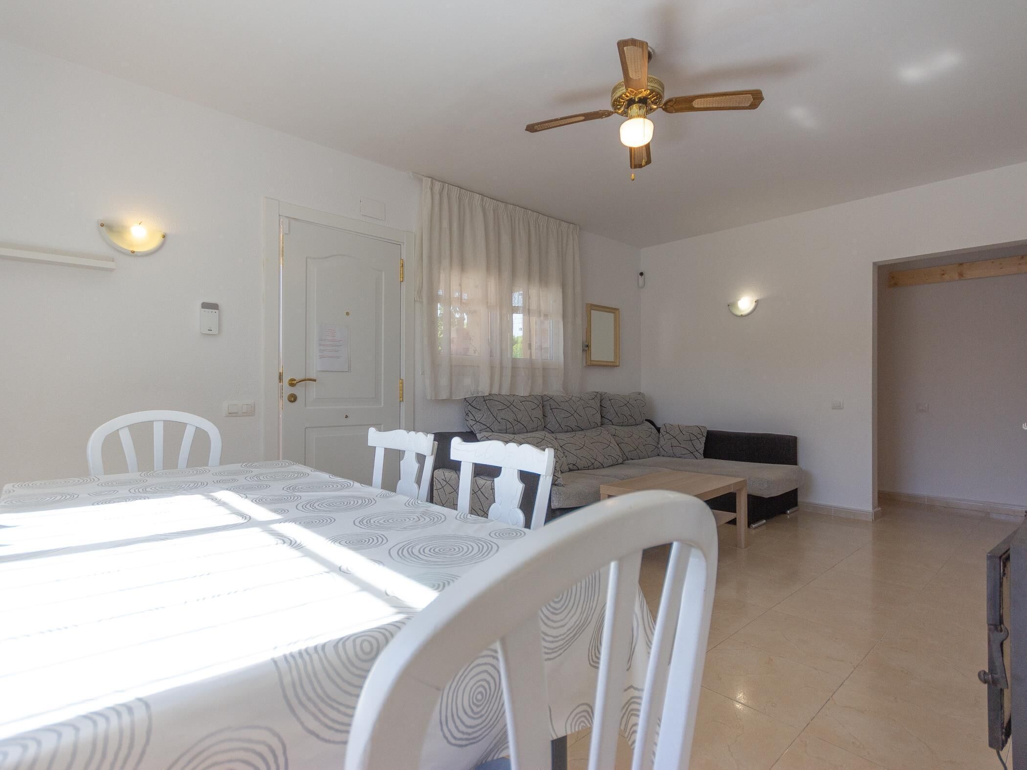 A dining area with a table, chairs, and a ceiling fan.