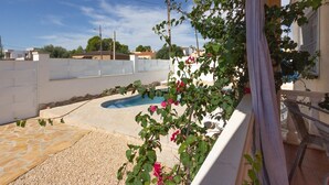 Ein Wohngrundstück mit Schwimmbad, einer weißen Mauer und einem Balkon mit einem Stuhl.
