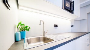 A modern kitchen with a stainless steel sink, a blue countertop, and a potted plant.
