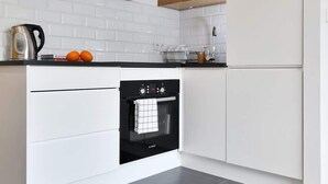 A modern kitchen with white cabinetry, a Bosch oven, and a black countertop.