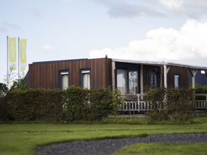 Guests can enjoy a sheltered porch area with a railing, surrounded by a well-maintained garden.