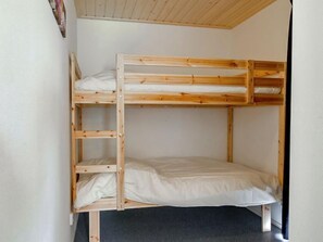 Un lit superposé avec une structure en bois et du linge de lit blanc.