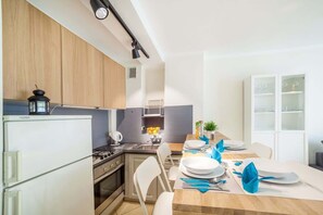 Een koelkast, een magnetron, een kookplaat, kookgerei, borden en bestek