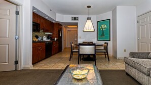 A living room with a dining table, chairs, a sofa, a bowl of popcorn, wooden cabinets, and a kitchen in the background. - Las Vegas | Vegas Nightlife Stay | Pool & Hot Tub | 1BR (Las Vegas)