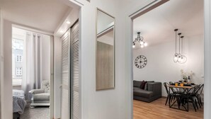 Un appartement moderne avec un plancher en bois, un coin repas comprenant une table et des chaises, un canapé gris et un grand miroir.