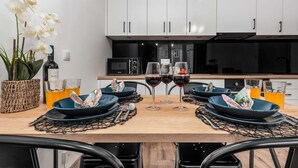 Une cuisine moderne avec des armoires blanches, un micro-ondes noir et une grande fenêtre.