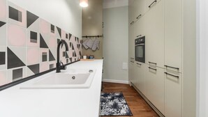 Una cocina moderna con encimera blanca, grifo negro y salpicadero con estampado geométrico.