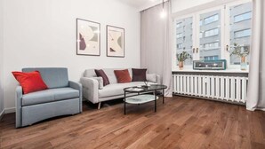 Una sala de estar moderna con dos sofás, una mesa de centro y una ventana con vista a edificios.