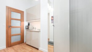 A compact kitchen with a wooden door, white cabinets, and a stainless steel refrigerator. - Stylish Apartment | Air Conditioning | Close Center (Warszawa)