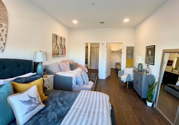 Un dormitorio moderno con una cama grande, mesitas de noche, un aparador y un vestidor.