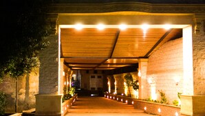 A covered outdoor area with a stone wall, a wooden roof, and a series of lights along the pathway. - Pyramids Tower (Giza)