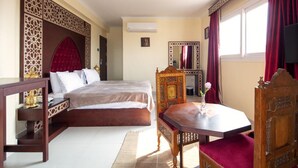 A bedroom with a bed, a wooden nightstand, a table with a chair, and a mirror. - Pyramids Tower (Giza)