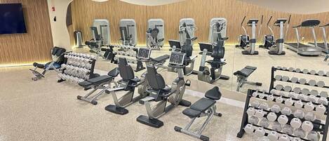 A gym with various exercise machines and dumbbells.