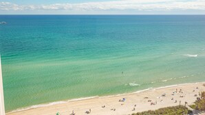 Een strand met helder turquoise water en een zandstrand.