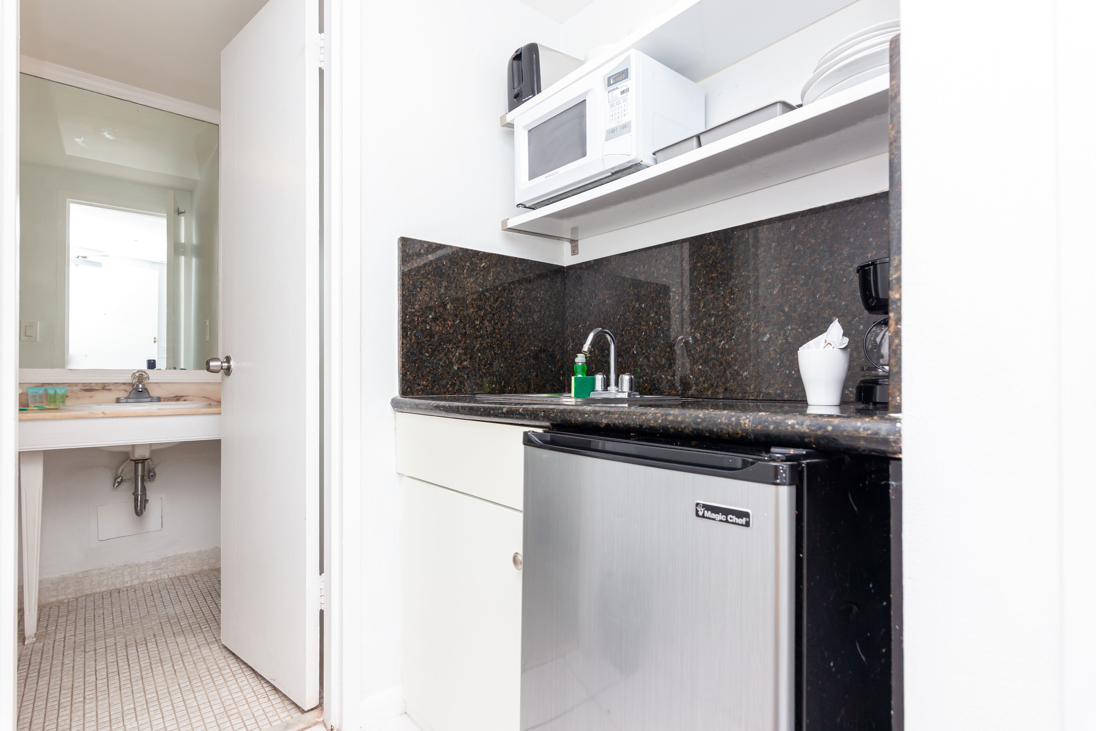 A compact kitchen with a microwave, sink, and a compact refrigerator.