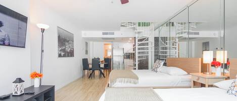 A modern hotel room with a bed, bedside table, lamp, and a view of the staircase.