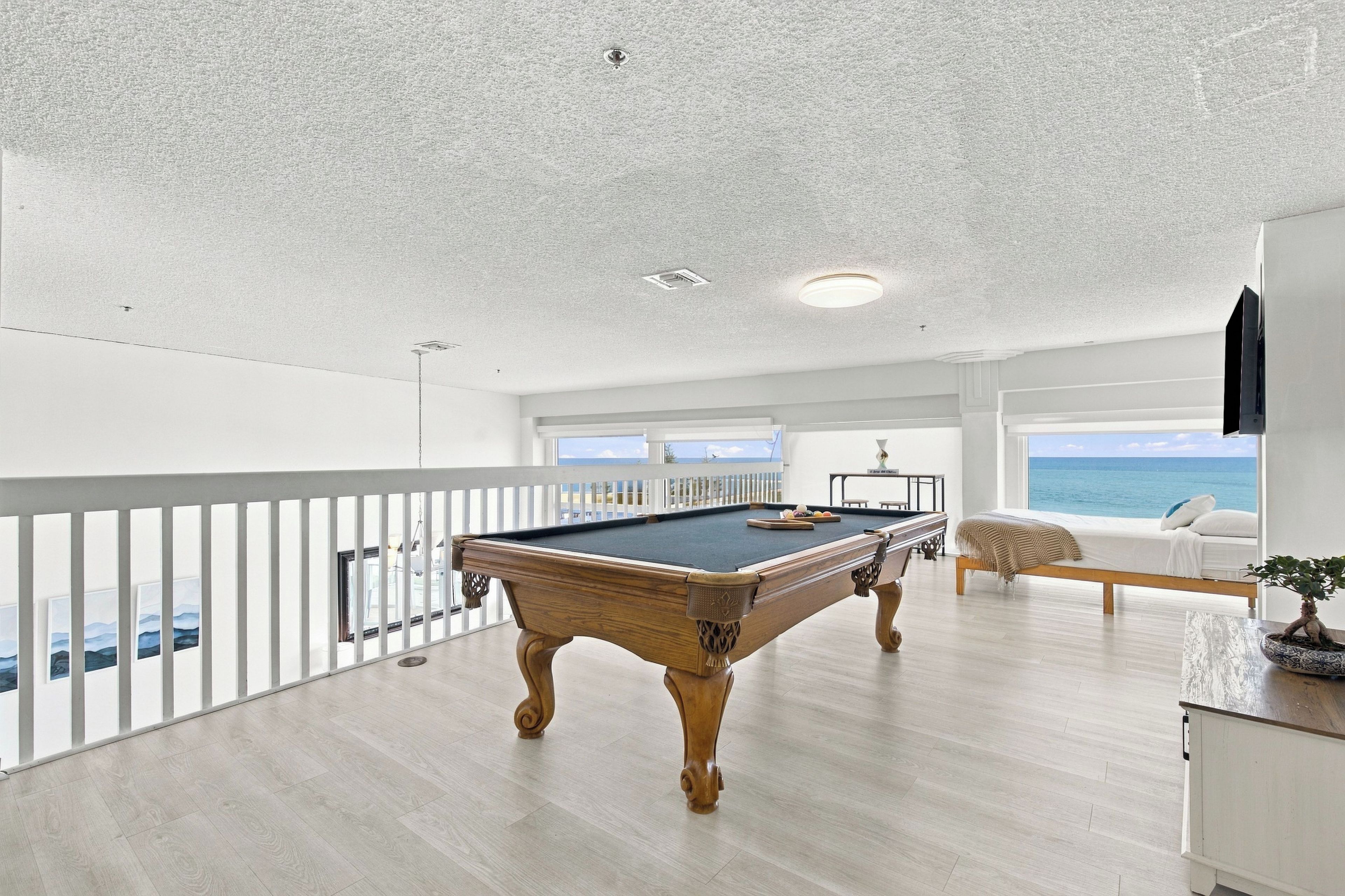 Ein Billardtisch in einem Raum mit Balkon mit Blick aufs Meer.