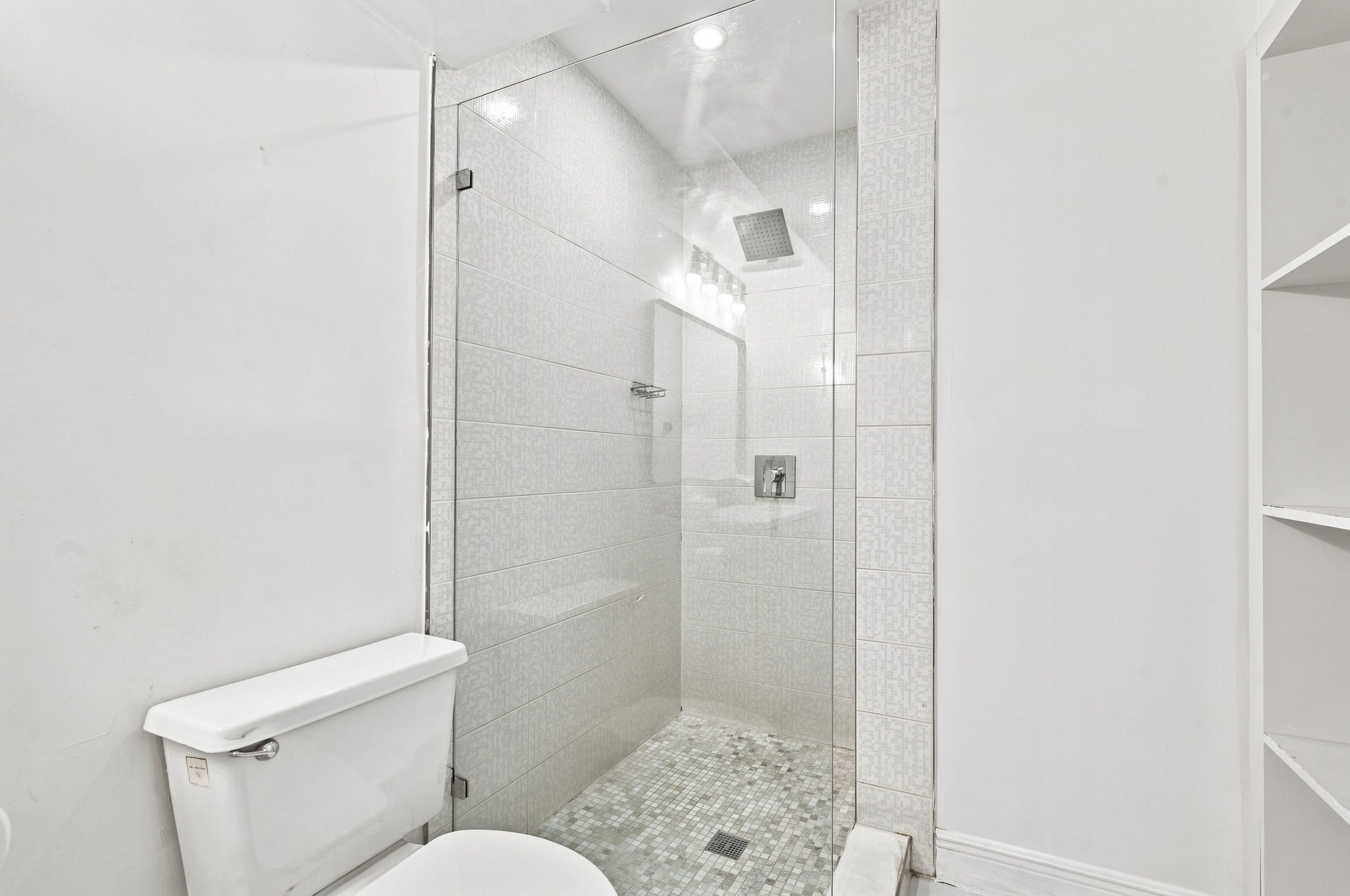Un bany modern amb dutxa tancada per vidre, un vàter i un lavabo.