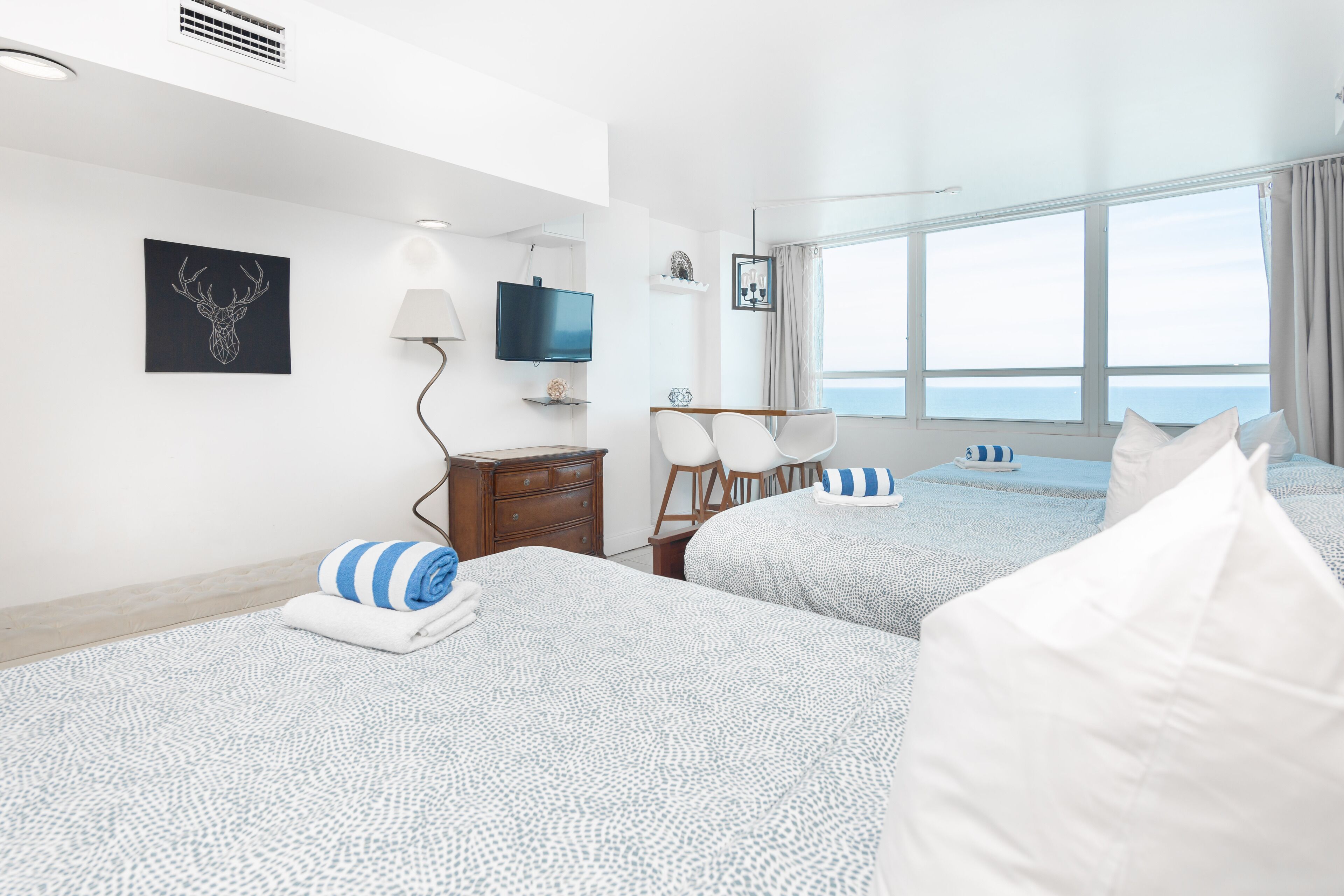 Hotellihuone, jossa on kaksi sänkyä, televisio, työpöytä ja ikkuna, josta on näkymä.