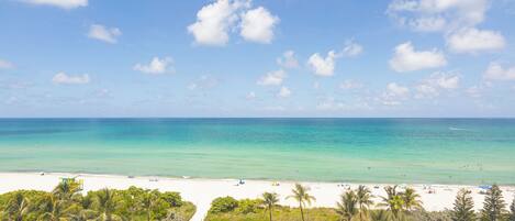 A beach with clear turquoise water, white sand, and palm trees.