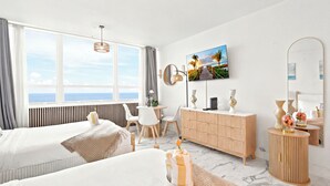 Hotelkamer met twee bedden, een zithoek, een televisie en een groot raam met uitzicht.