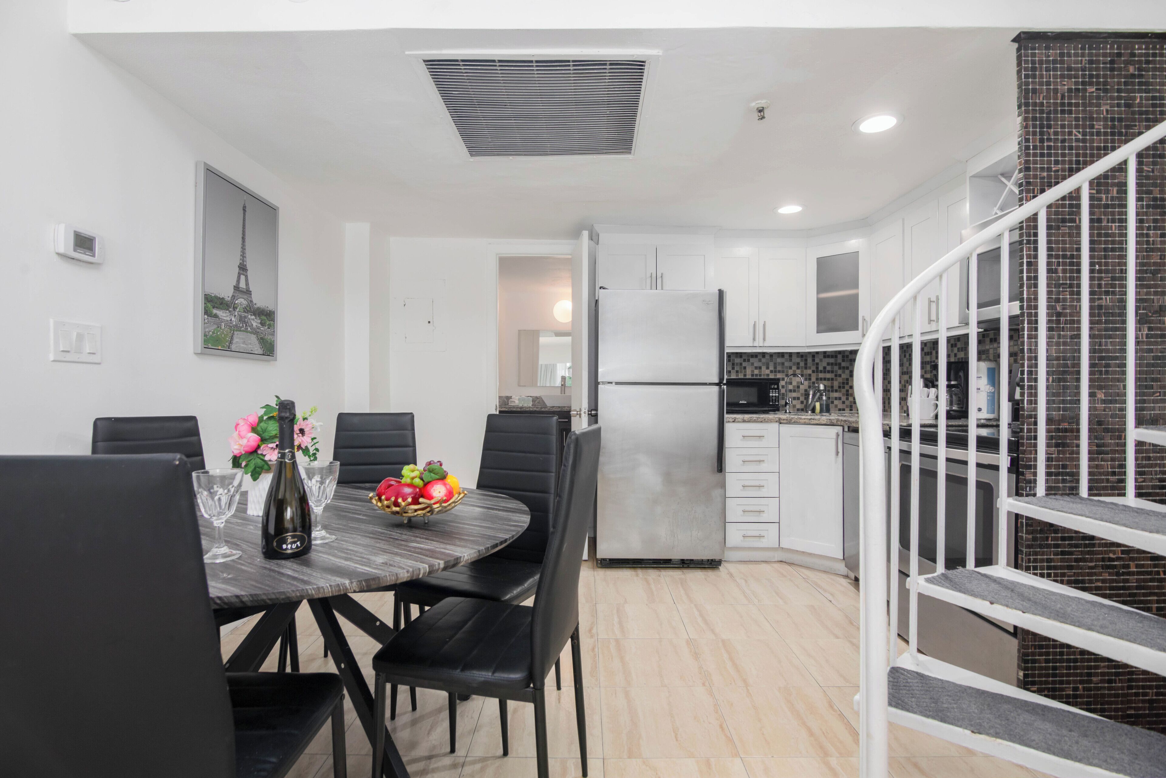 A modern kitchen with a built-in refrigerator, white cabinets, and a black countertop.