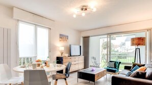 Una sala moderna con una mesa de comedor redonda, un sofá y un televisor.