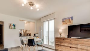 Una sala de estar moderna con comedor, televisor y obras de arte en las paredes.