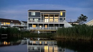 A two-story building with a balcony and a reflection in the water.