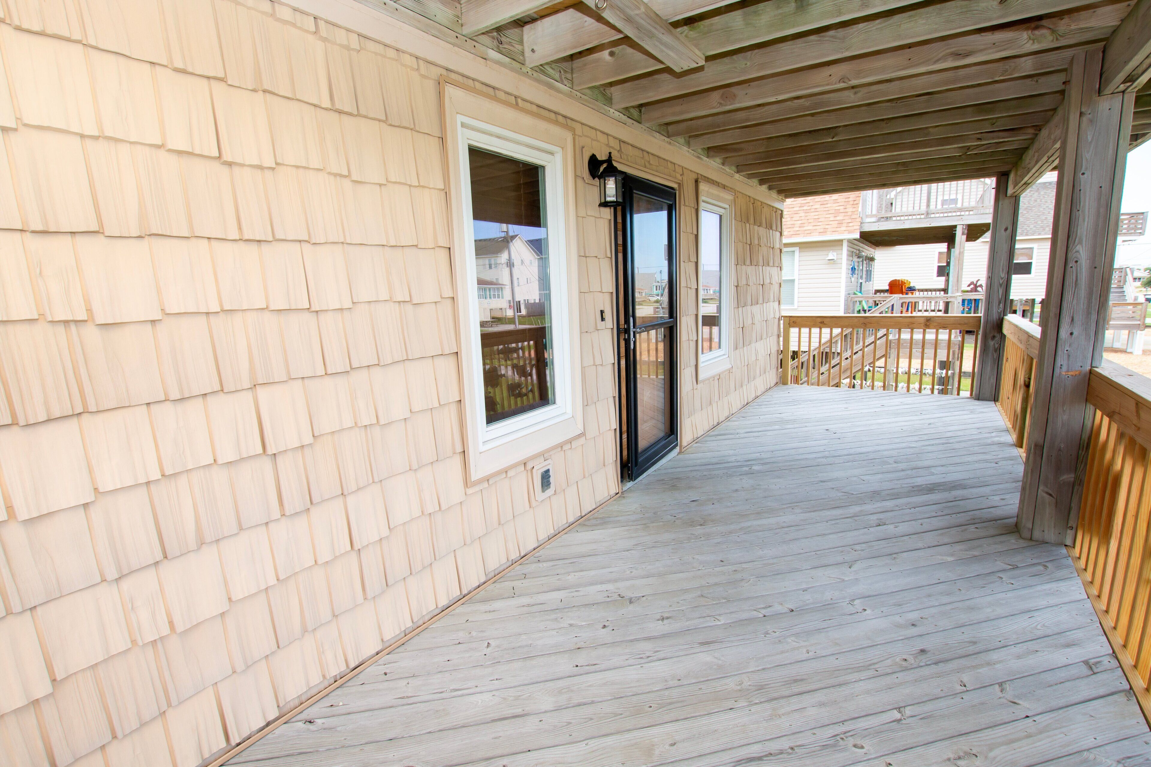 A wooden deck with a covered area, a door, and a window.