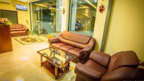 A modern living room with a brown leather sofa, a glass coffee table, and a television mounted on the wall.