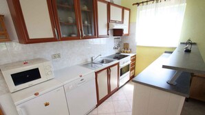 Una cocina compacta con electrodomésticos blancos, armarios de madera y un ventanal pequeño.
