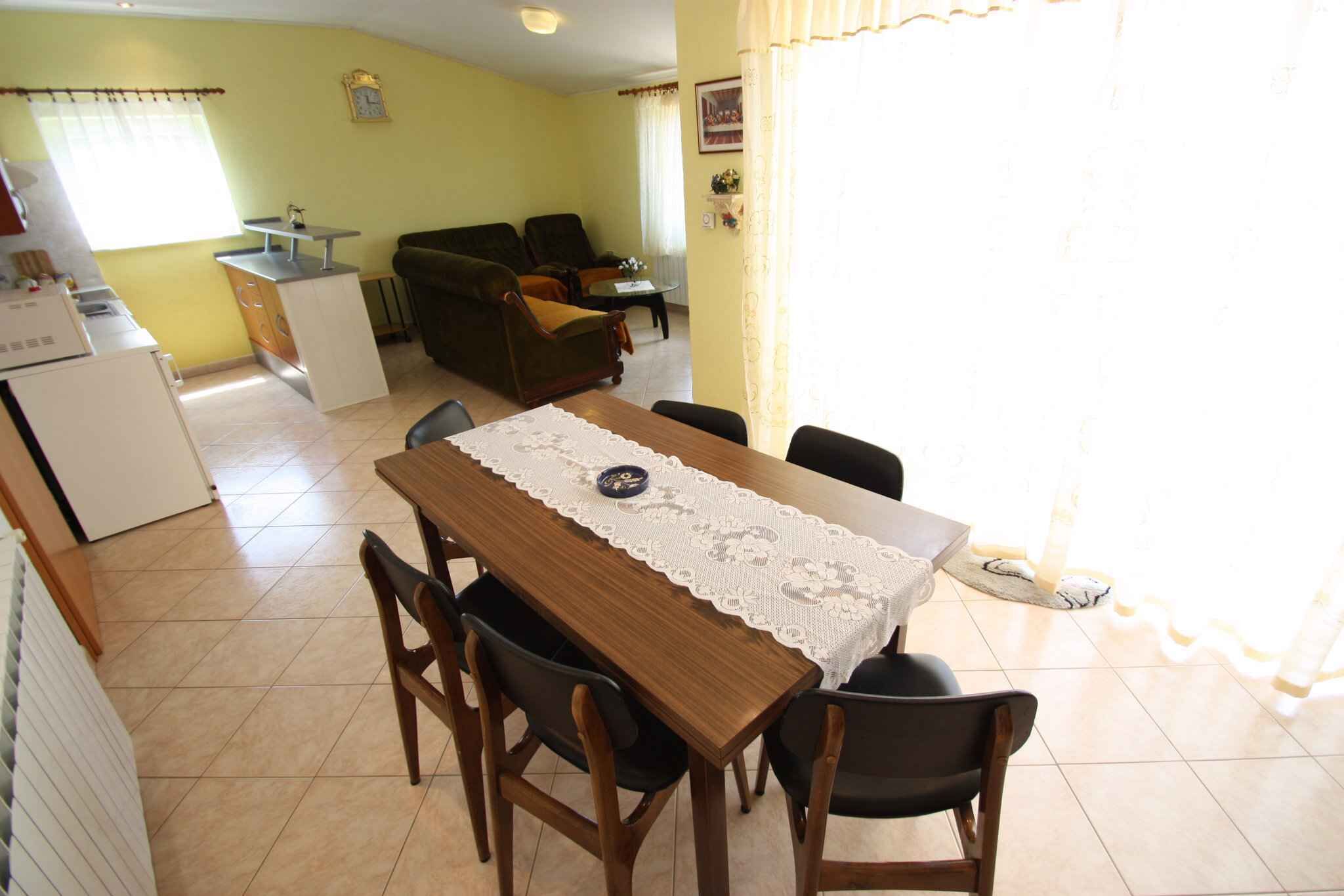 A dining area with a wooden table, four chairs, and a lace tablecloth.