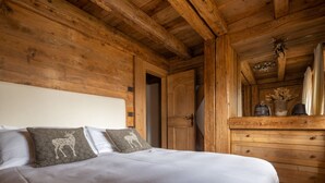 A wooden cabin interior with a bed, pillows, a wooden dresser, and a door. - Cortina Lodge Stunning View R&R (Cortina d´Ampezzo)