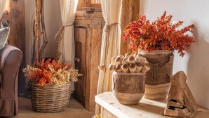 A rustic interior with wooden furniture, a woven basket with dried flowers, and a wooden table with a vase of red flowers. - Cortina Lodge Stunning View R&R (Cortina d´Ampezzo)