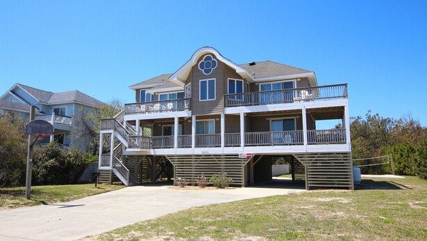 A two-story waterfront house with a balcony, a basketball hoop, and a clear sky. - Oceanside, Screened Porch Dining, Priv Pool, Yard, WW1042, Jolly Octopus (Corolla)