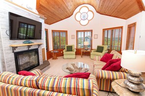 A living room with a fireplace, television, and striped sofas.