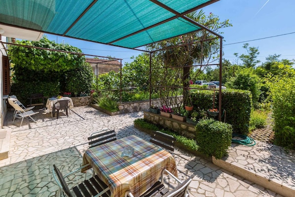Relax in the serene outdoor patio, surrounded by lush greenery and a stone-tiled floor.