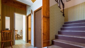 A staircase with wooden steps and a handrail, leading to a room with a wooden door and a chair. - Holiday home mit Klimaanlage und Grill (Jadranovo)