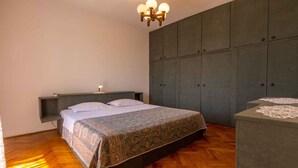 A bedroom with a bed, a nightstand, a dresser, and a wardrobe. - Holiday home mit Klimaanlage und Grill (Jadranovo)