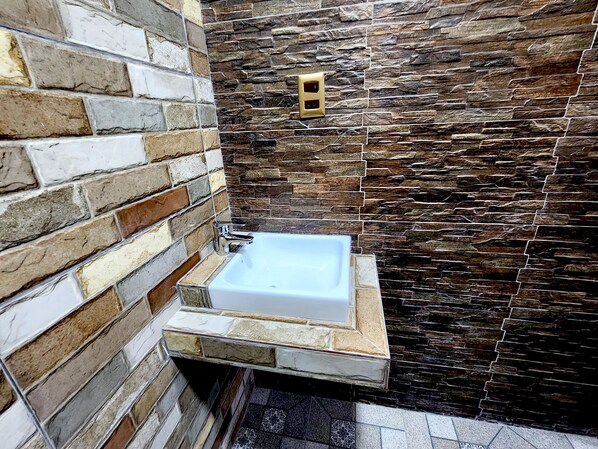 A bathroom with a stone wall, a sink, and a shower area.