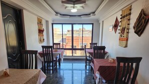 Uma área de refeições com mesas e cadeiras, uma janela grande com vista e painéis decorativos na parede.