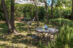 A round metal table with chairs, a hammock, and a small table with a lantern. - Holiday home 80 m from the sea (Crikvenica)