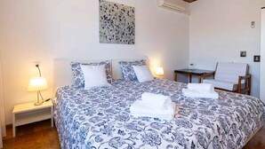 A bedroom with a large bed, two bedside tables with lamps, a chair, and a small table. - Holiday home 80 m from the sea (Crikvenica)