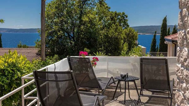 An outdoor patio with two chairs and a table, overlooking a body of water and hills. - Holiday home 80 m from the sea (Crikvenica)