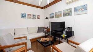 A living room with a sofa, two armchairs, a coffee table, a TV, and artwork on the wall. - Holiday home 80 m from the sea (Crikvenica)