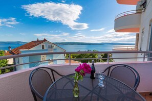 Enjoy a romantic dinner for two on this balcony overlooking a serene body of water and distant hills.