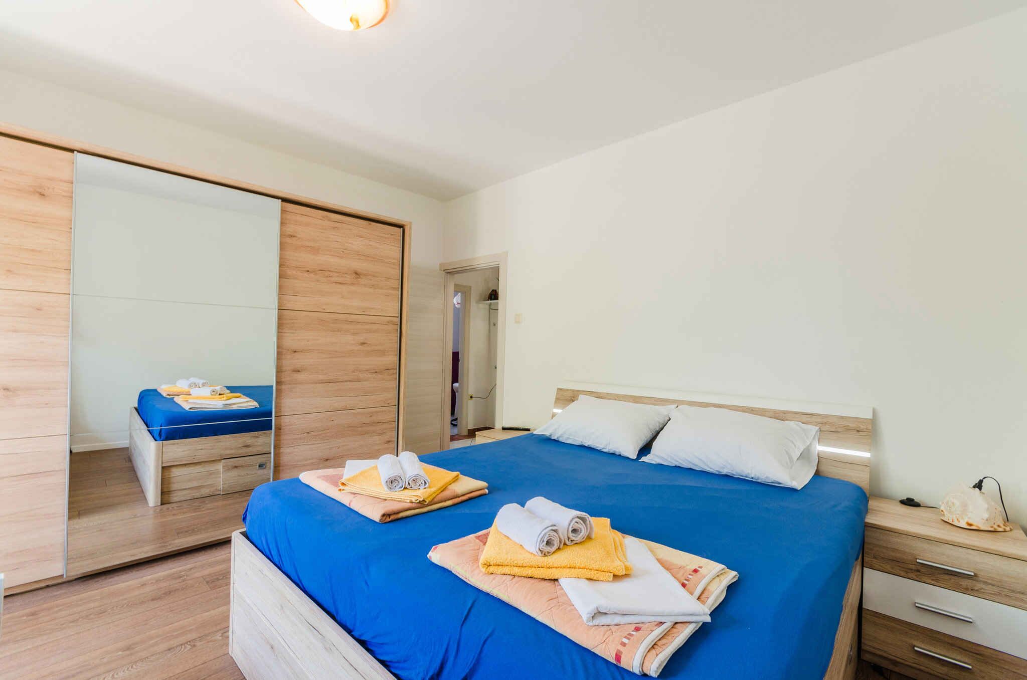 A modern bedroom with a large bed, a wardrobe, and a mirror.