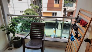 Un balcone con una sedia, una pianta in vaso e un appendiabiti con abiti.