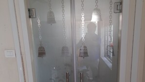 Una stanza con una porta in vetro, dotata di due maniglie e il riflesso di una persona.